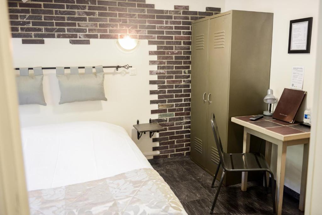 a bedroom with a bed and a desk with a laptop at Logis Le Saint Hubert in Haybes