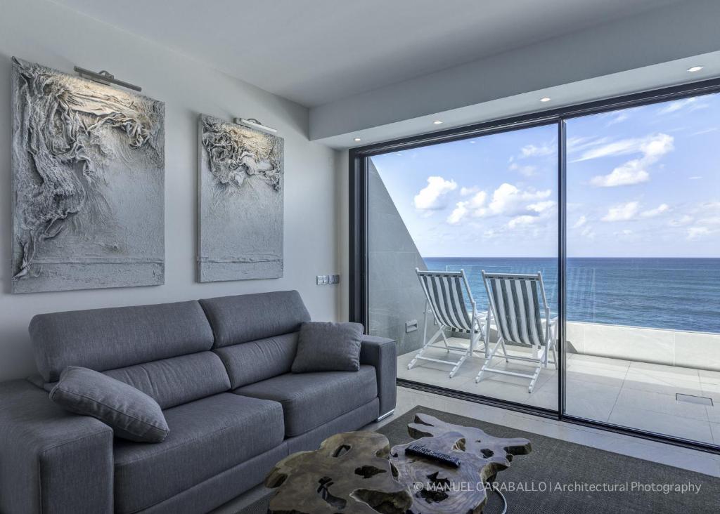 Penthouse Over The Sea في لاس بالماس دي غران كاناريا: غرفة معيشة مع أريكة وإطلالة على المحيط