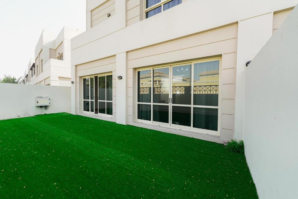 a large white building with a green lawn at Havana Villas Al Barsha in Dubai