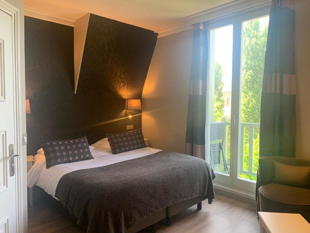 a bedroom with a bed and a large window at Villa Augeval Hôtel de charme & Spa in Deauville