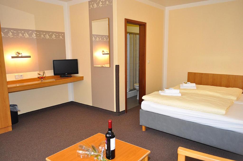 Una habitación de hotel con una cama y una mesa con una botella de vino en Gästehaus Lietzow & Störtebeker Camp, en Lietzow