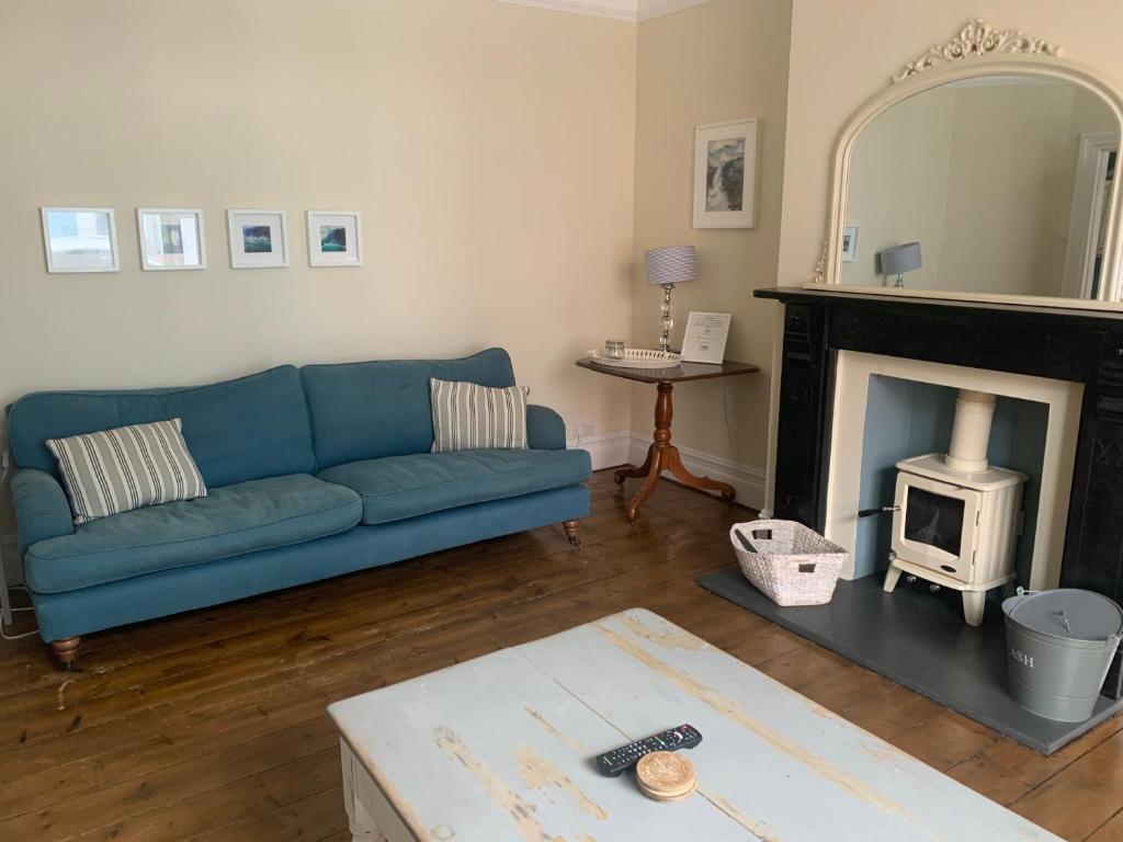 a living room with a blue couch and a fireplace at Beautiful Tenby House, pets allowed in Tenby