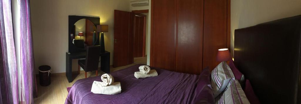 Un dormitorio con una cama morada con toallas. en Prestige for Home Apt 1 Quarteira, en Quarteira