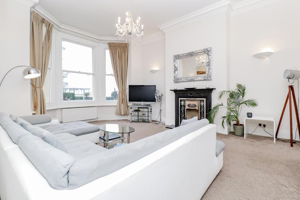 a white living room with a white couch and a fireplace at 3 Queens Gardens Sea View Apartment in Eastbourne
