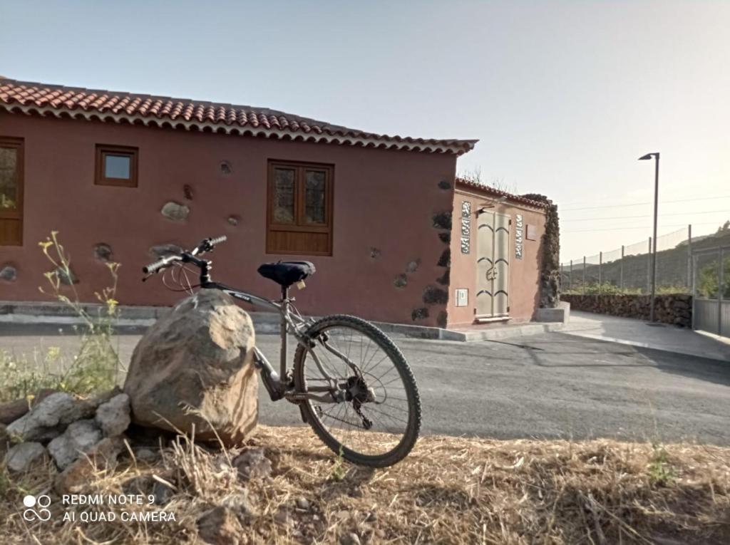 Casa La Cañada في سانتياغو ديل تيدي: دراجة متوقفة بجانب صخرة أمام منزل
