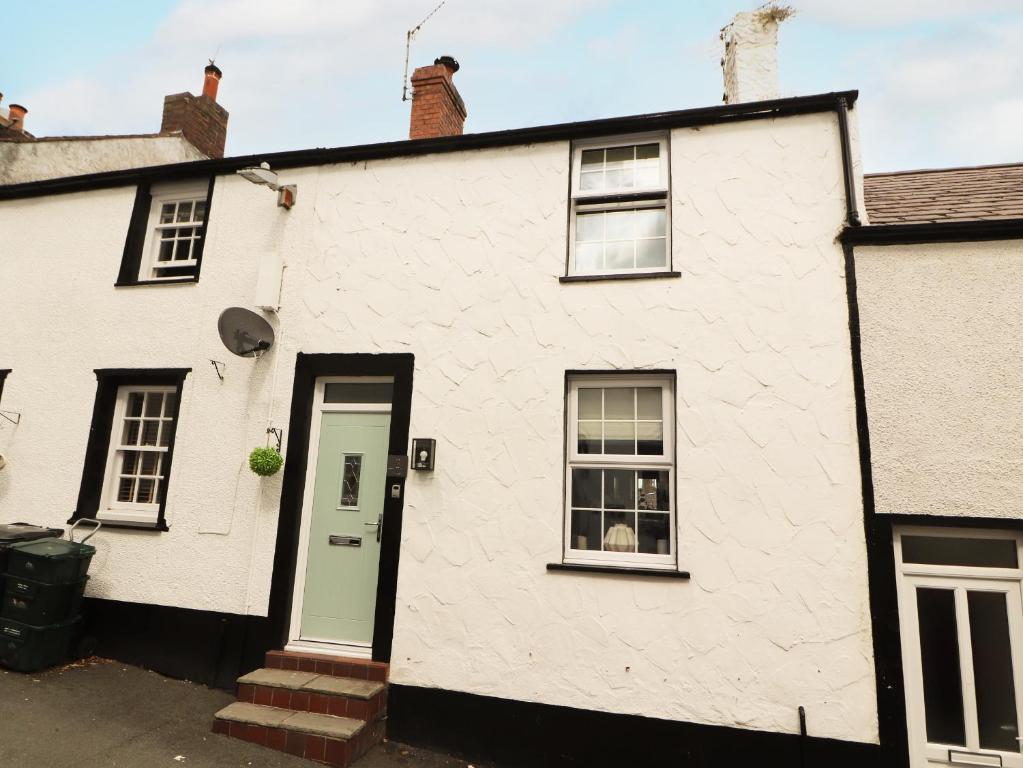 a white brick house with a green door at 8 Watkin Street in Conwy