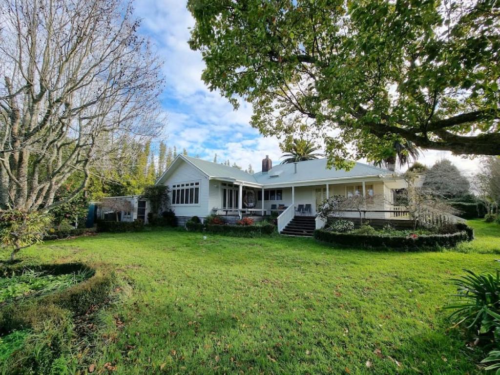 a white house with a yard at Country Garden Oasis with Parking and Wi-Fi in Taupaki