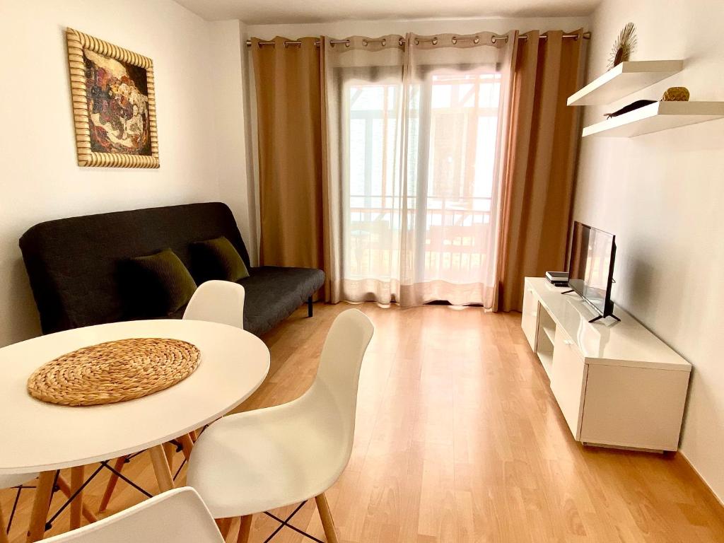 een woonkamer met een tafel en een televisie bij Apartamento acogedor en el centro de Cambrils in Cambrils