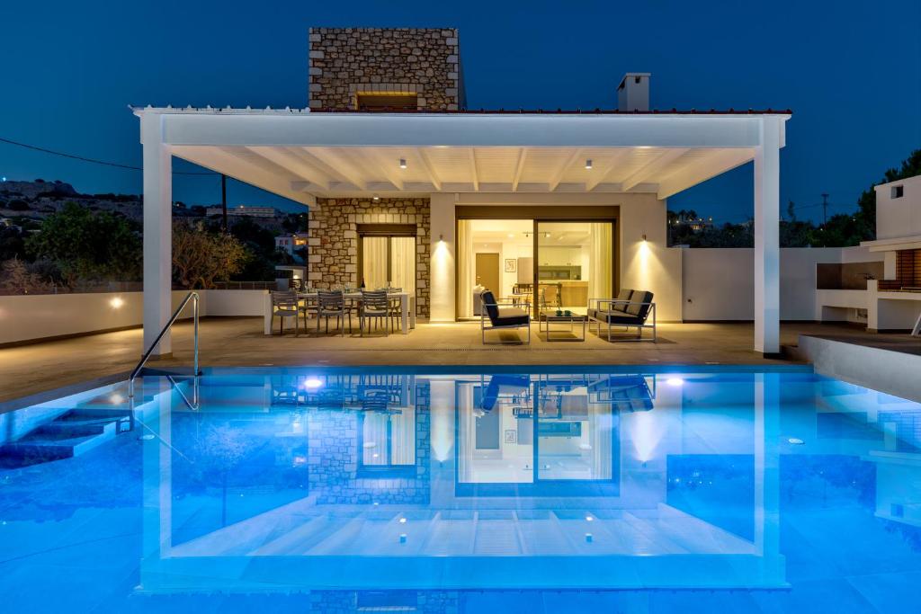 a villa with a swimming pool at night at Villa AmberBlue Pefkos in Pefki