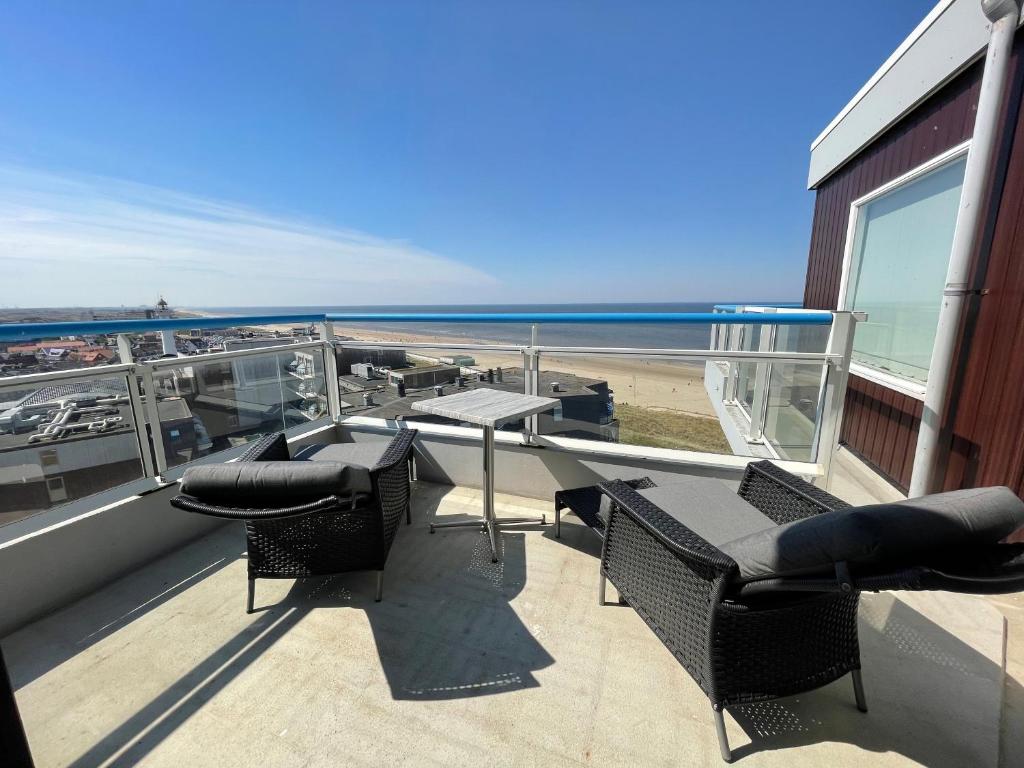 a balcony with a table and chairs and the beach at Droomvakanties Egmond Zeezicht in Egmond aan Zee