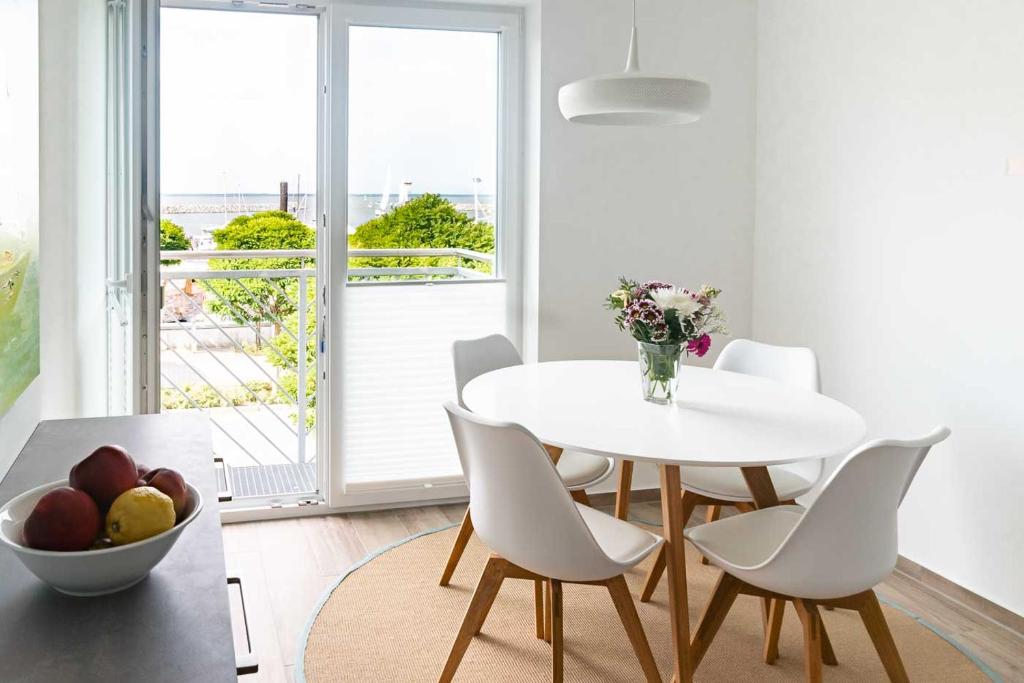 - une salle à manger blanche avec une table et des chaises blanches dans l'établissement Heimathafen, à Barth