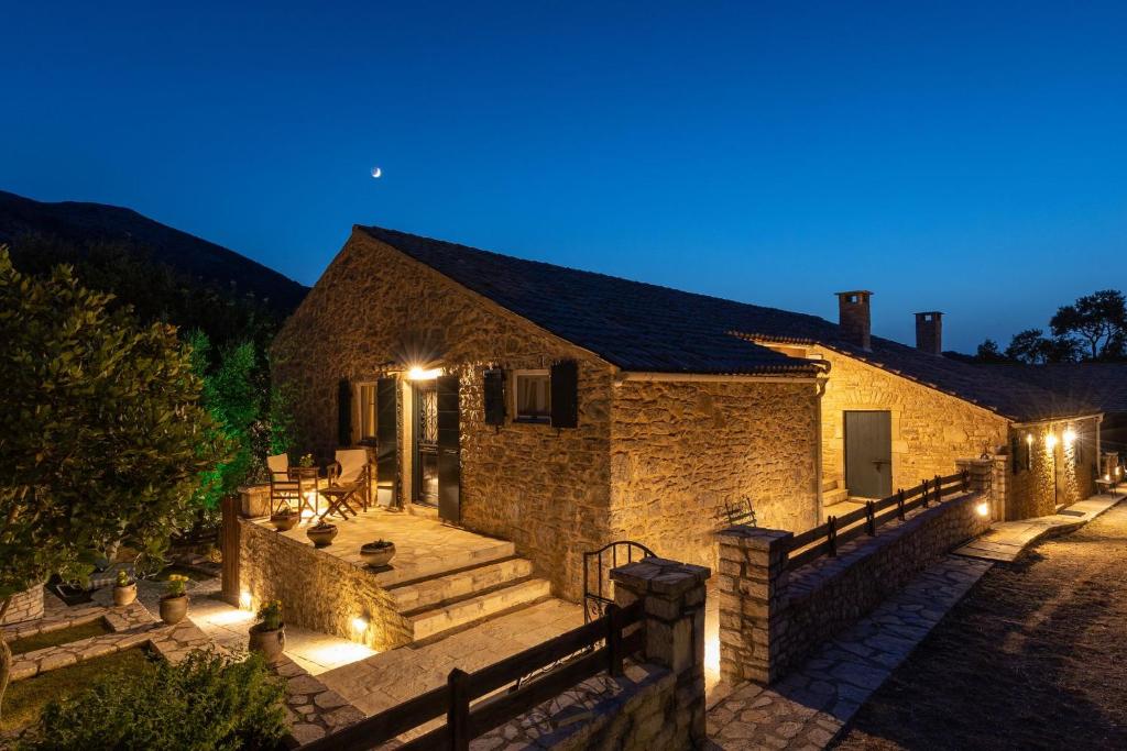 uma casa de pedra com escadas e luzes à noite em The Merchants House em Perítheia