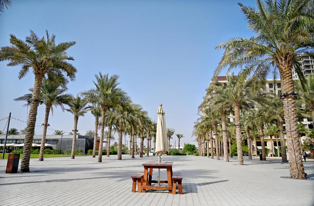 a park with a table and palm trees and a building at Al Qudra Town Square 2 Bedroom Duplex Apartment Dubai in Dubai