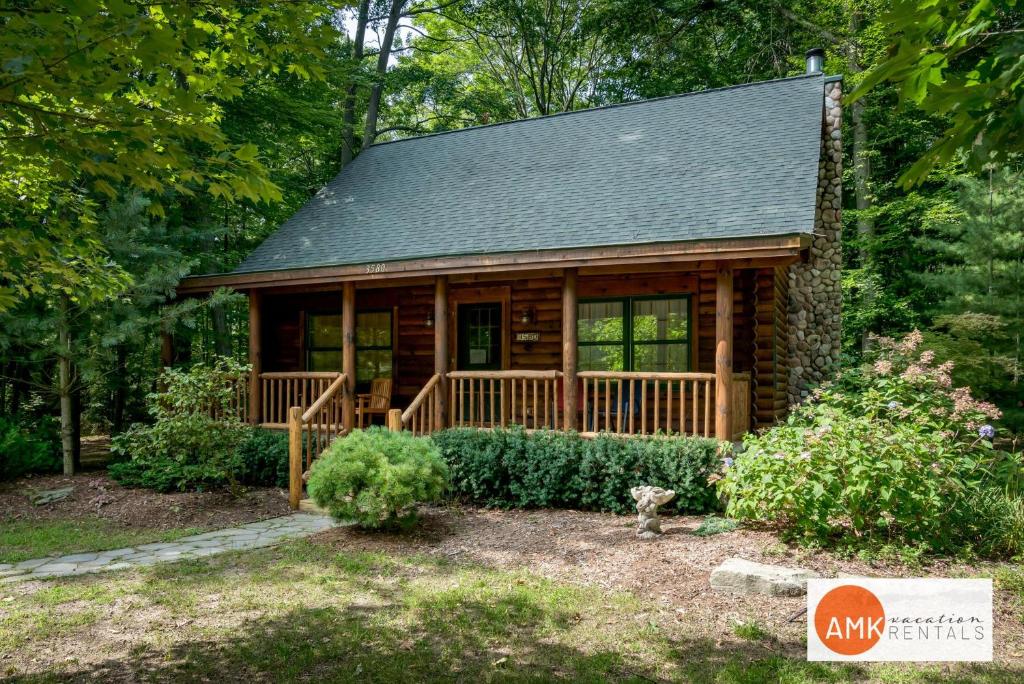 a log cabin in the woods with a porch at Wonderful Log Cabin near private beach and lake access in Saugatuck