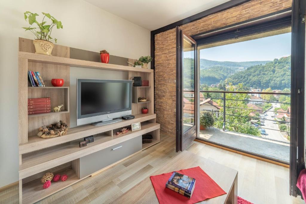 a living room with a television and a large window at Apartments Vidik in Ivanjica