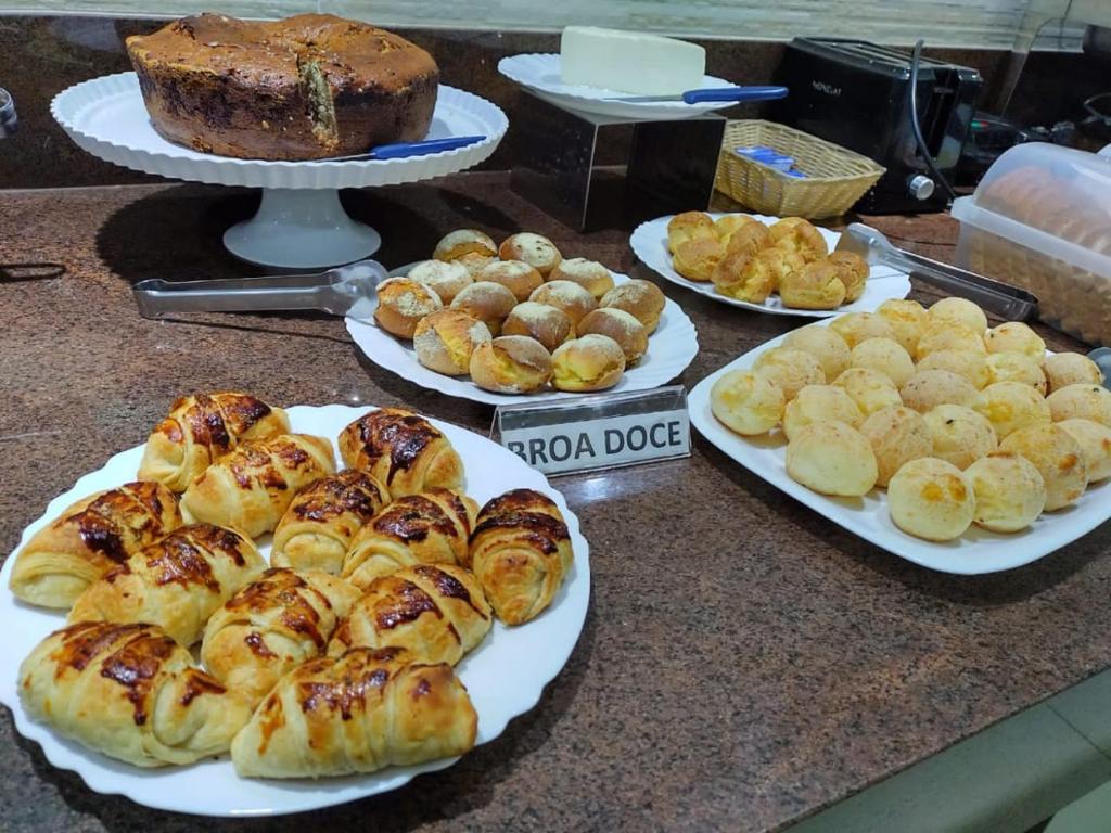 uma mesa com pratos de pão, pastelaria e bolos em Patos Hotel em Patos de Minas