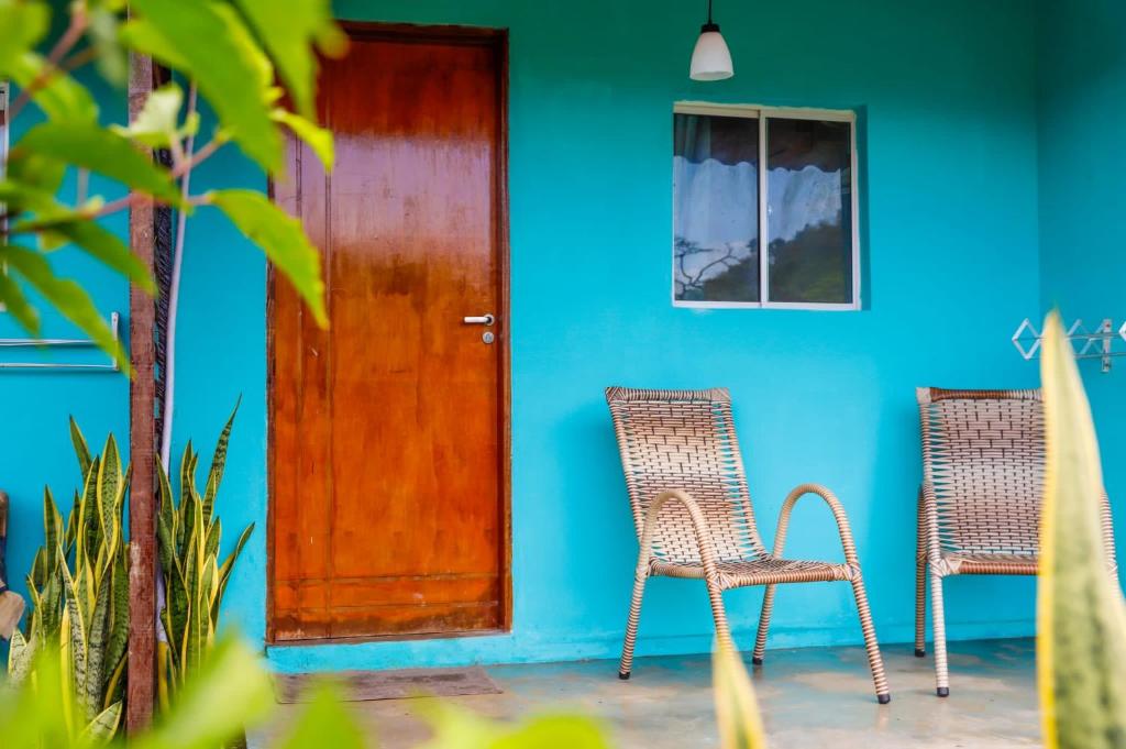 uma casa azul com duas cadeiras e uma porta de madeira em CASA PITANGA em Fernando de Noronha