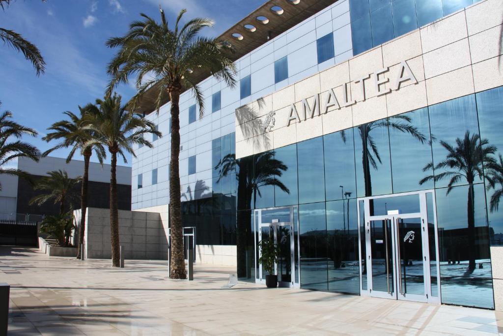 ein Gebäude mit Palmen davor in der Unterkunft Hotel Amaltea by Executive Sport in Lorca
