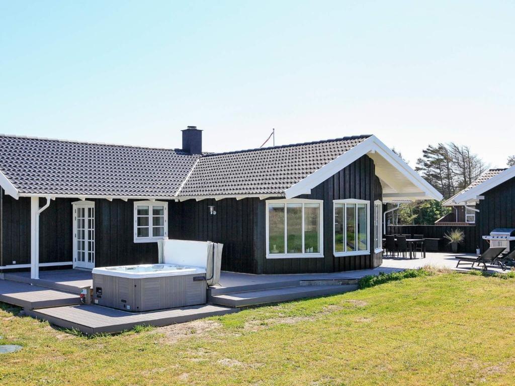 una casa negra con bañera de hidromasaje en el patio en 10 person holiday home in Saltum, en Saltum