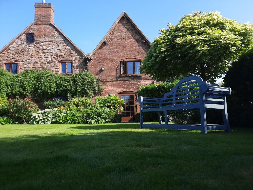 eine blaue Bank, die vor einem Haus sitzt in der Unterkunft Hood Lane Farm B&B in Arley