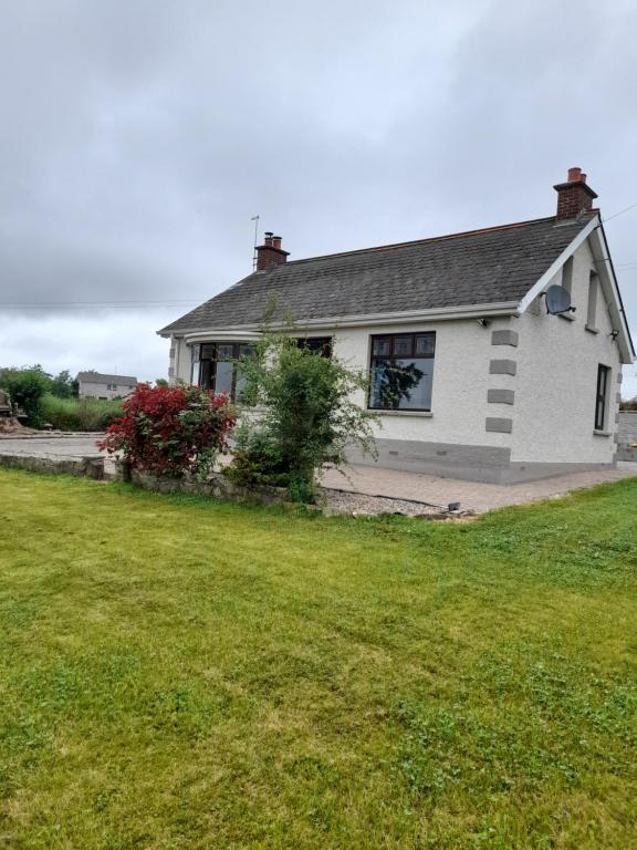 ein weißes Haus mit einem Rasenplatz davor in der Unterkunft Maryrose cottage in Rasharkin