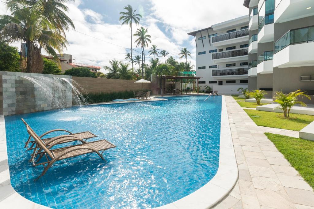 a swimming pool with a bench and a water fountain at Aloha Residence in Porto De Galinhas