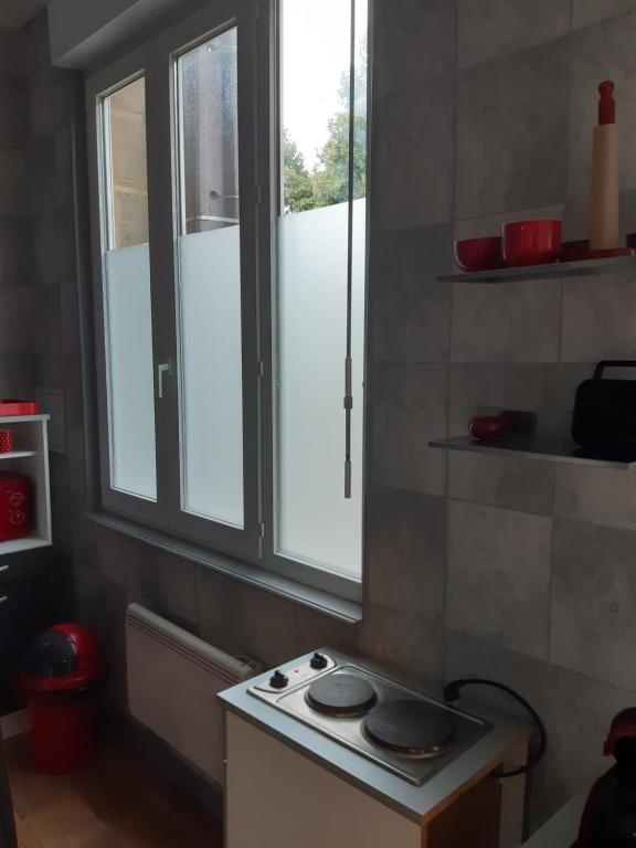 una pequeña estufa en una cocina con 2 ventanas en MAISON Studio SEDAN Meublé 14M2 INDEPENDANT, en Sedan