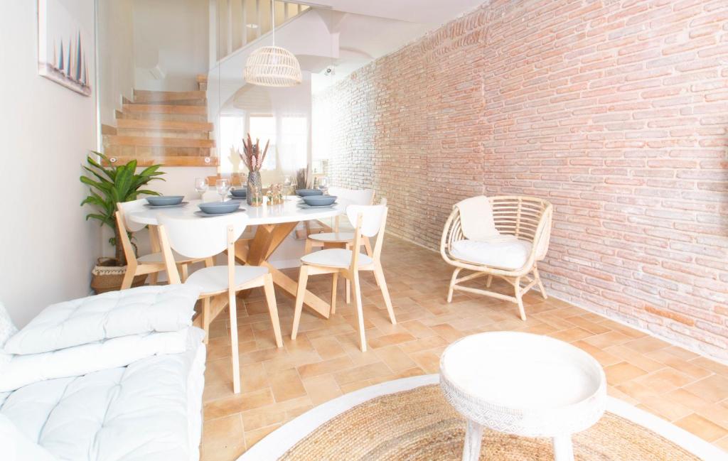 een eetkamer met een bakstenen muur en een tafel en stoelen bij Allegra Boutique House in Palamós