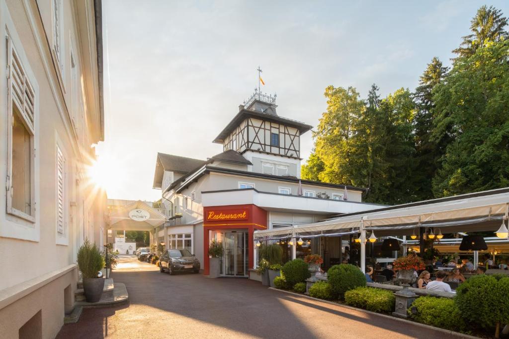 budynek z wieżą zegarową na szczycie ulicy w obiekcie Hotel Post Wrann w mieście Velden am Wörthersee