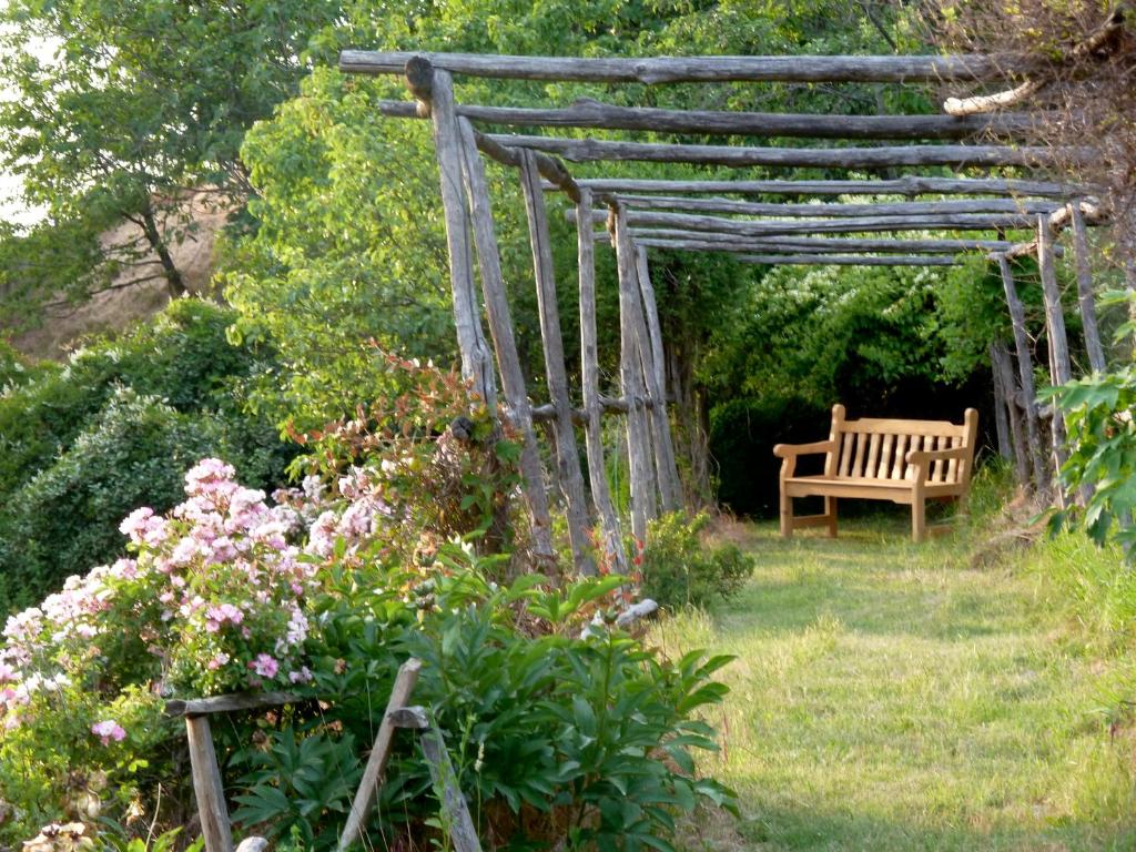 uma pérgola de madeira com um banco num jardim em B&B Al Giardino Dei Mandorli em Prasco