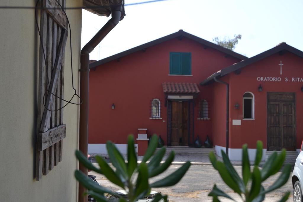 un edificio rojo con un cactus delante en Agriostello Riparo, en Anzio