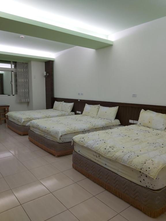 three beds are lined up in a room at Happy Heart B&amp;B in Taitung City