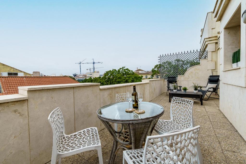 a patio with a table and chairs on a balcony at MalagaSuite Soho apartment in Málaga