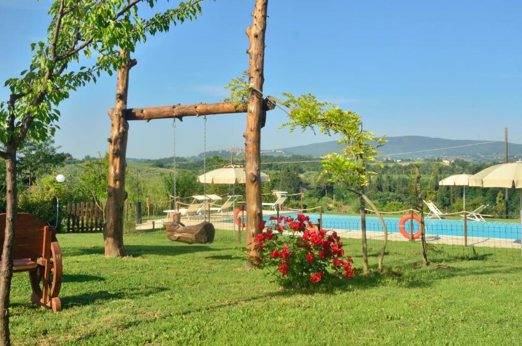 a garden with a swing and a swimming pool at Fattoria Antonella in San Gimignano