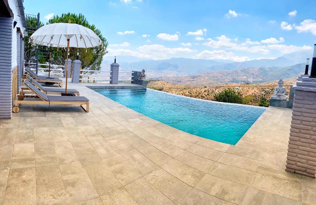 uma piscina com um guarda-sol e uma cadeira e um guarda-sol em Casa Eden - Mountain View, Infinity Pool em Málaga