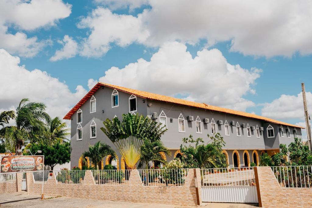 a large building with a fence in front of it at Pousada e Restaurante Manaím in Passa e Fica