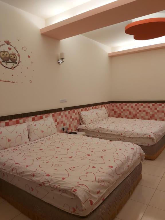 a bedroom with two beds and a couch at Happy Heart B&amp;B in Taitung City