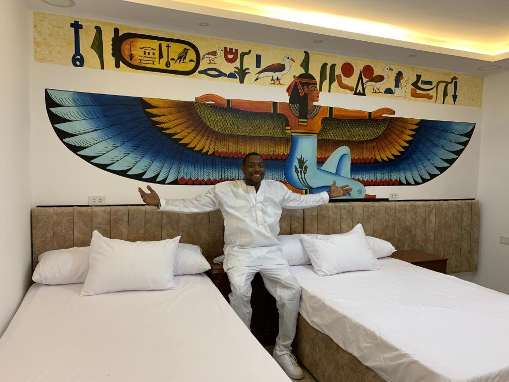 a man sitting between two beds in a hotel room at pyramids gardens guest house in Cairo