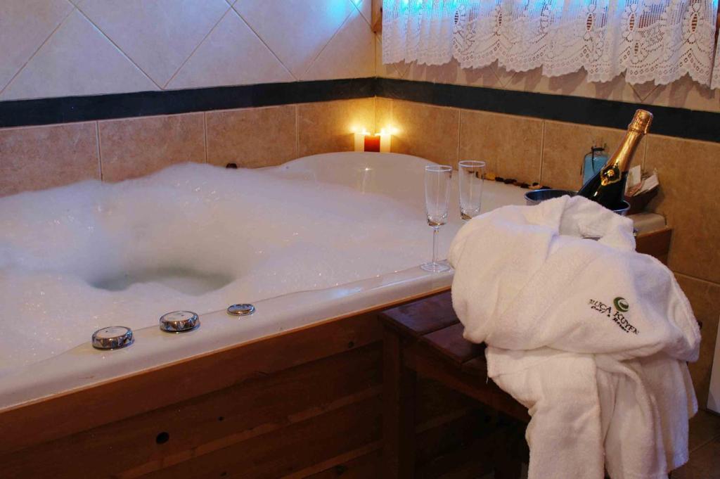 - une baignoire avec une bouteille de champagne et une serviette dans l'établissement Cabañas Ruca Kuyen Golf & Resort, à Villa La Angostura