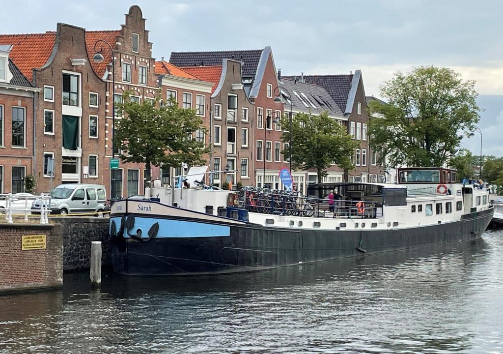 un barco está atracado en el agua cerca de edificios en Hotelboat Sarah en Ámsterdam