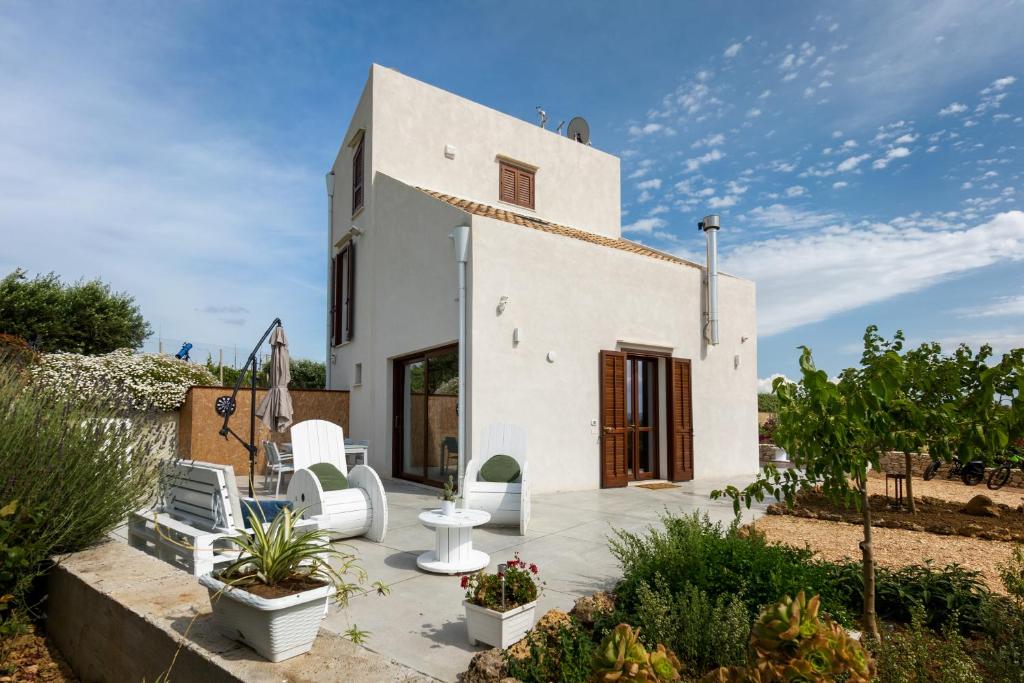 een wit huis met twee witte stoelen op een patio bij Zu Bastianu House in Alcamo
