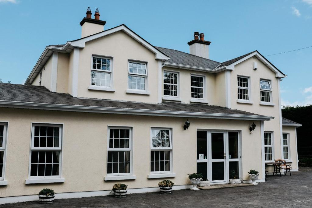 a white house with black windows and plants at Glenhill B&B in Wexford