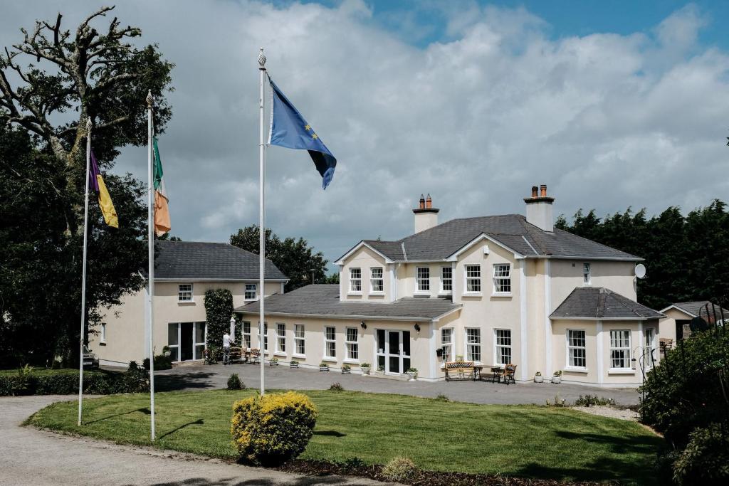 Uma casa branca com uma bandeira azul à frente. em Glenhill B&B em Wexford