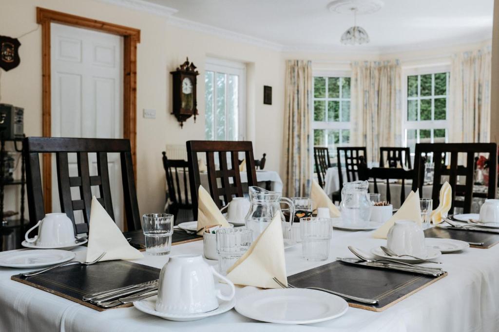 a dining room with a table with white plates and napkins at Glenhill B&B in Wexford