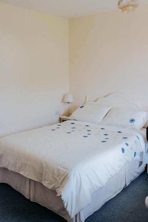 a bedroom with a white bed with blue flowers on it at Glenhill B&B in Wexford