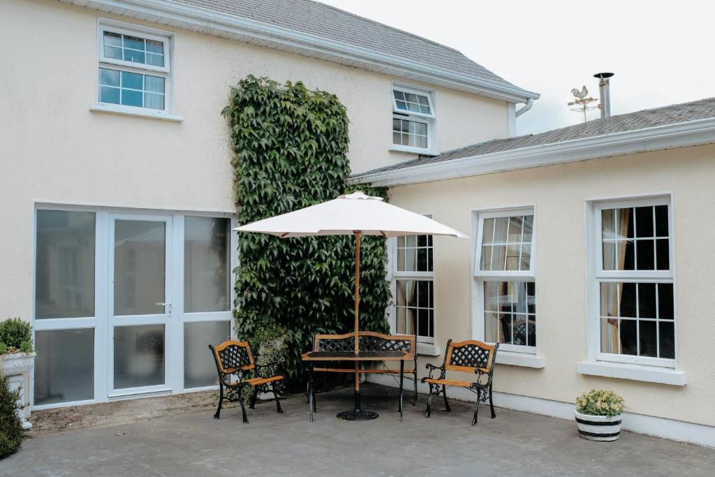 a table and chairs with an umbrella in front of a house at Glenhill B&B in Wexford