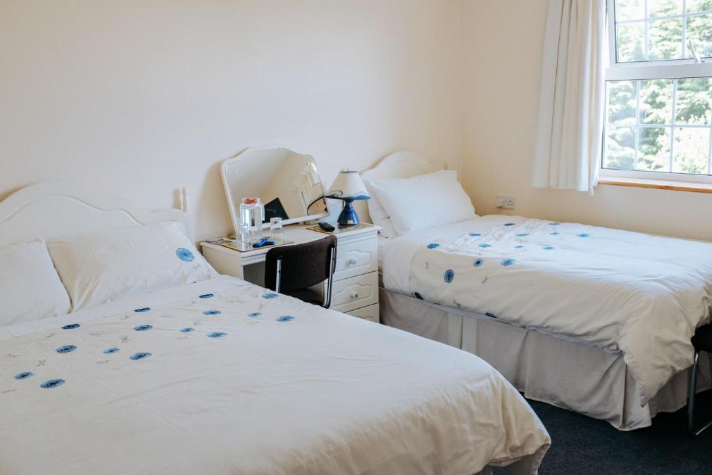 a bedroom with two beds and a desk and a window at Glenhill B&B in Wexford