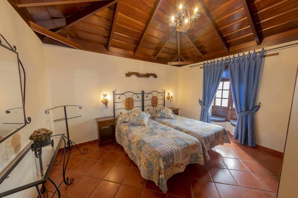 1 dormitorio con 1 cama en una habitación con cortinas azules en Casa Rural Monte del Agua en Los Silos