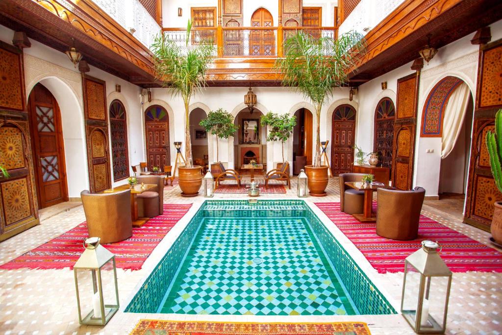 uma piscina interior num edifício com cadeiras e mesas em Riad Melhoun & Spa em Marraquexe