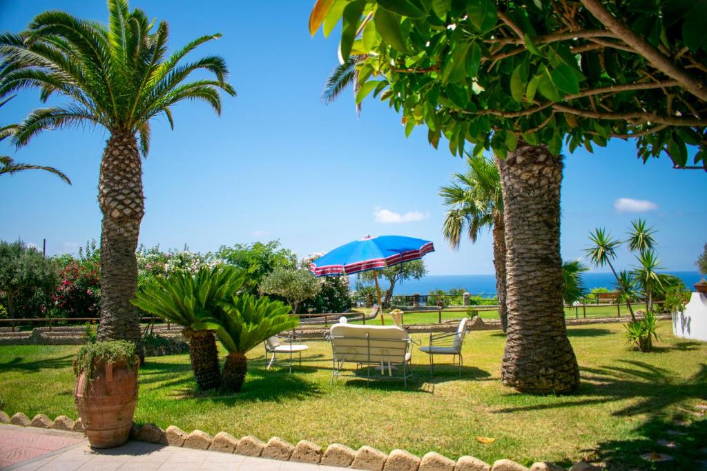 a group of palm trees with a table and a blue umbrella at Hotel Villa Rita in Ischia